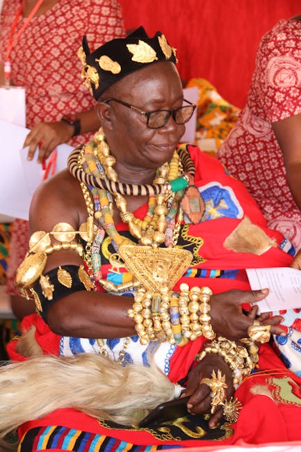 Interior scene showing a person performing surface cleaning or sanitisation in a room with vibrant red fabric drapes and patterned cushions. The individual is wearing traditional attire with gold jewe